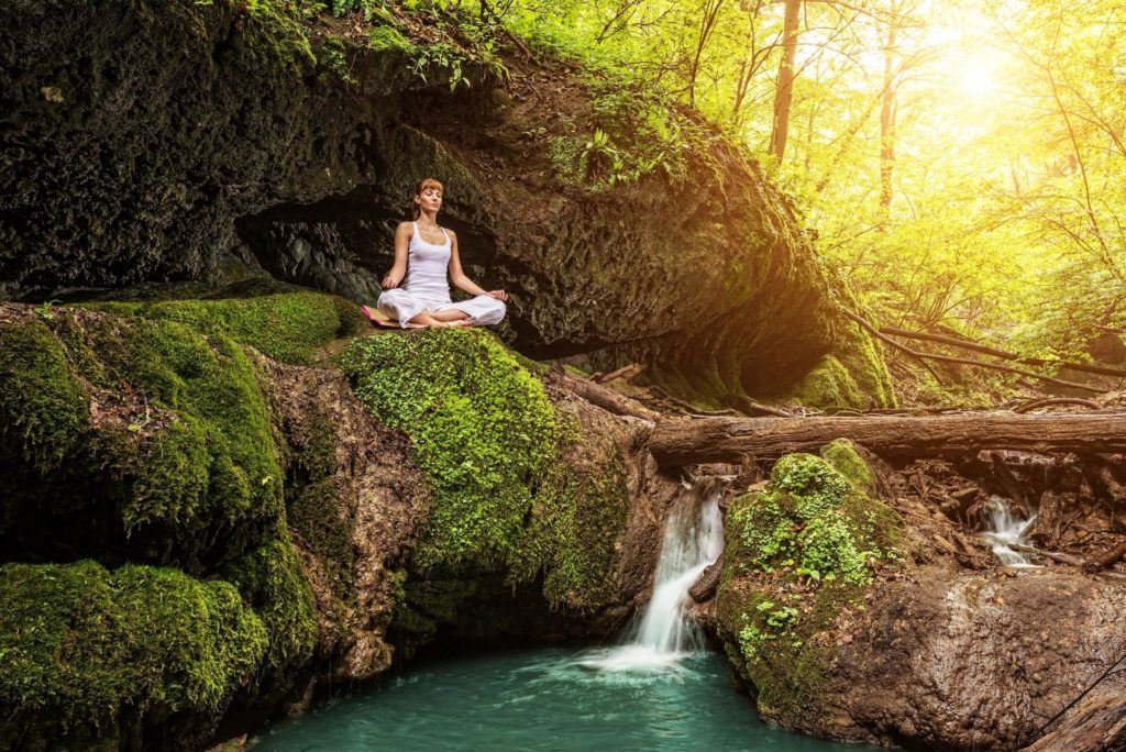 Woman meditating at waterfall